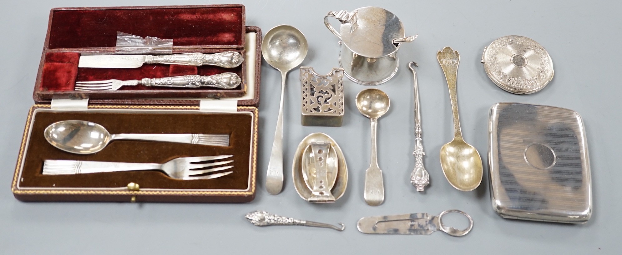 A small collection of sundry silver items including flatware, compact, cigarette case, mustard pot, sterling folding spoon, match sleeve, book mark, cased spoon and fork and a cased Victorian spoon and fork.